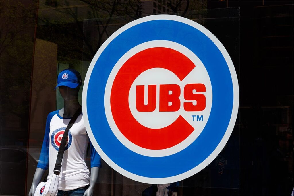 A storefront display featuring a mannequin dressed in a Cubs shirt and cap, with a large Cubs logo on the store window.