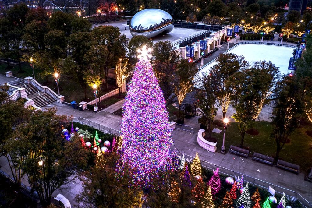 Chicago's Christmas tree in Millennium Park lit with lights beside Cloud Gate and the ice rink - aerial view at dusk