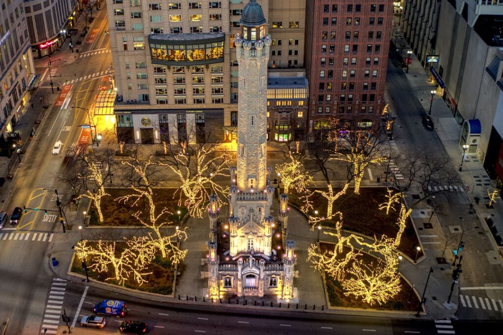 Chicago Water Tower and surrounding trees lit with Christmas lights, seen from above at night